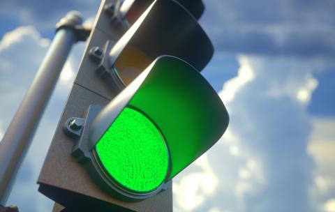 Green traffic light with blue sky background