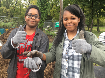 Two youth outdoors with work gloves