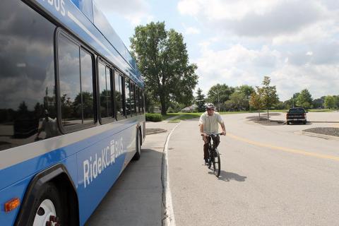 Bicyclist riding on road next to bus