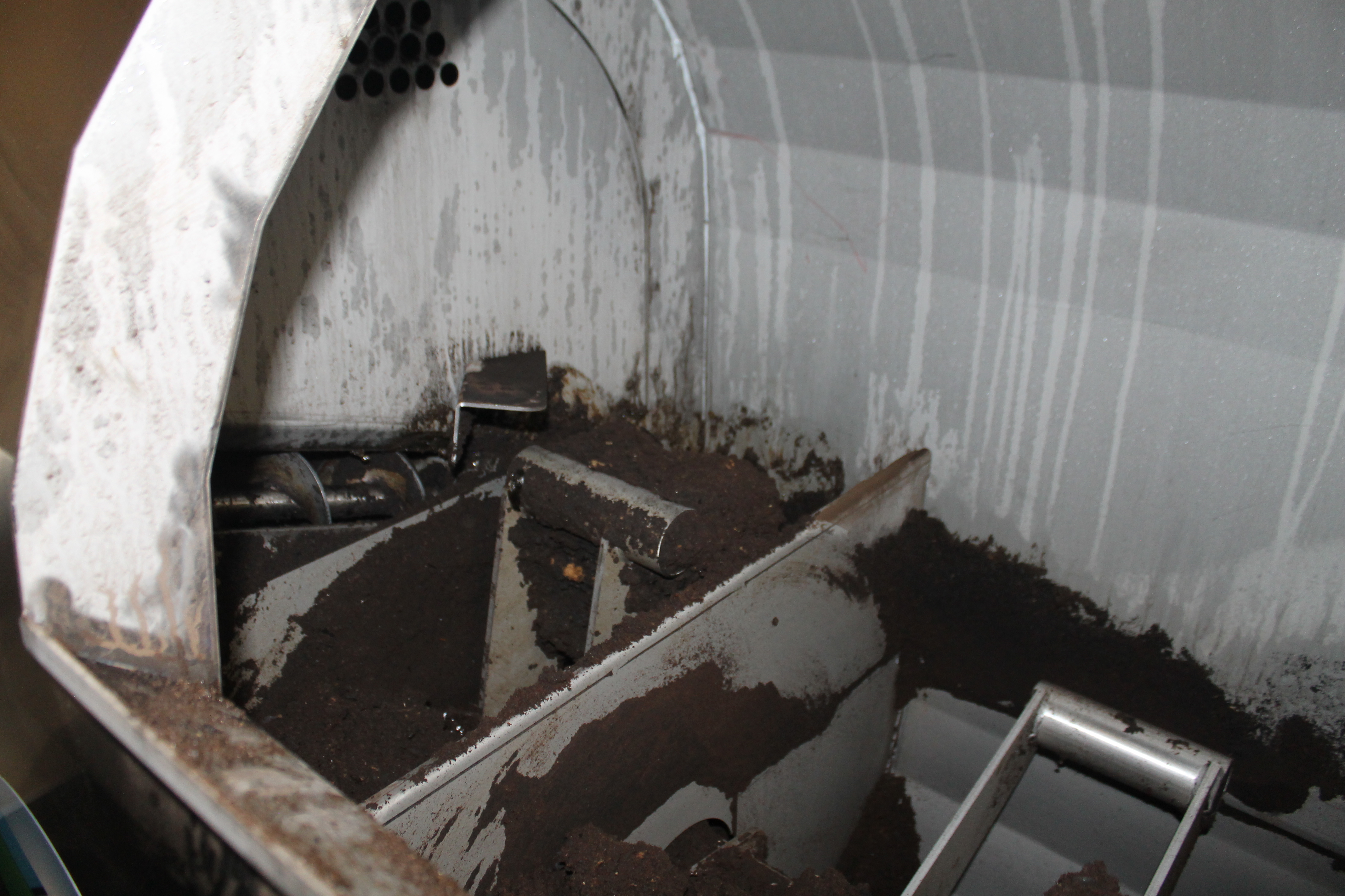 Inside the biodigester machine, mechanical rotary tillers churn material into powder inside separate chambers