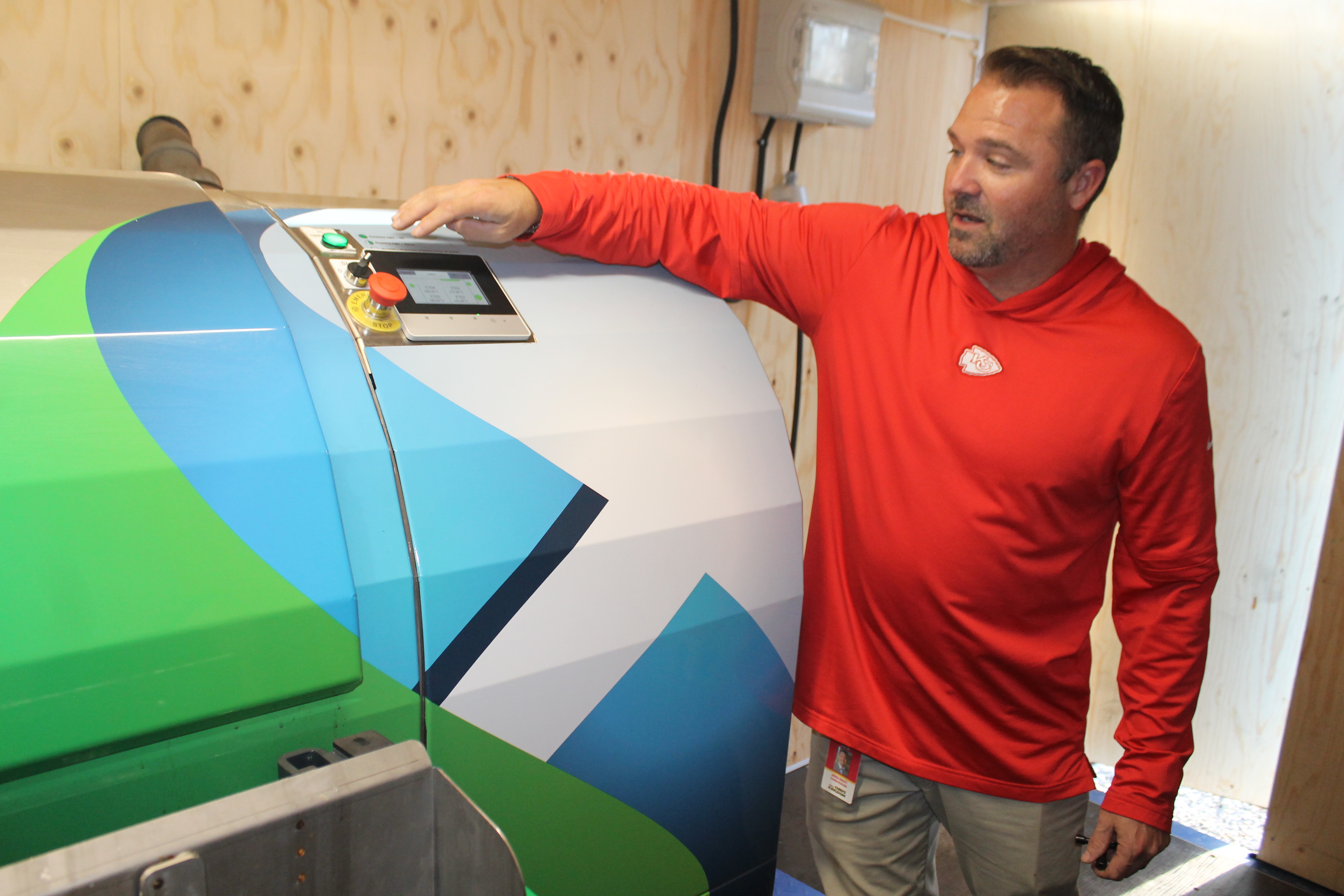 Jarrod Gravatt of the Kansas City Chiefs stands at one of the new biodigester machines, pointing to the control unit.