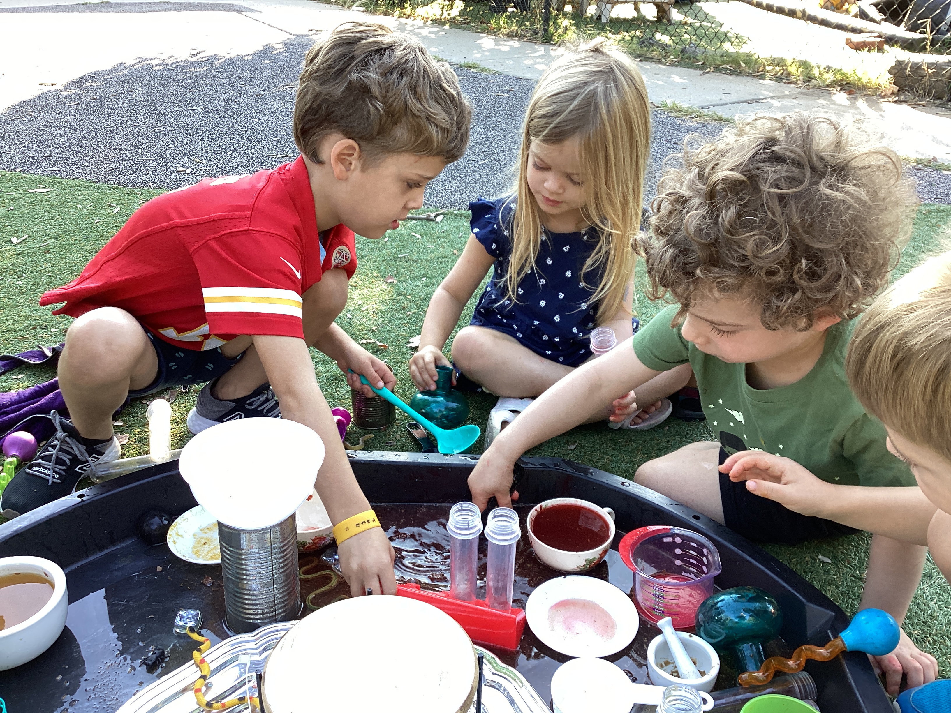 A group of young children playing in a water table with various household items