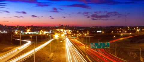 Time lapse of cars on highway at dusk with skyline in distance