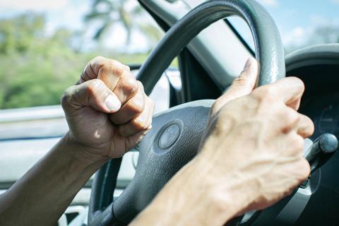 A person making a fist while behind a steering wheel