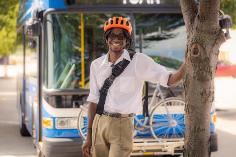 A man wearing a bike helmet standing in front of a Ride KC bus