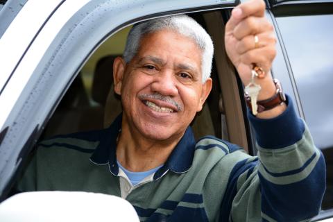 An older driver in a car holding keys