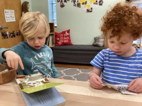 Two young children interacting with board books in a classroom