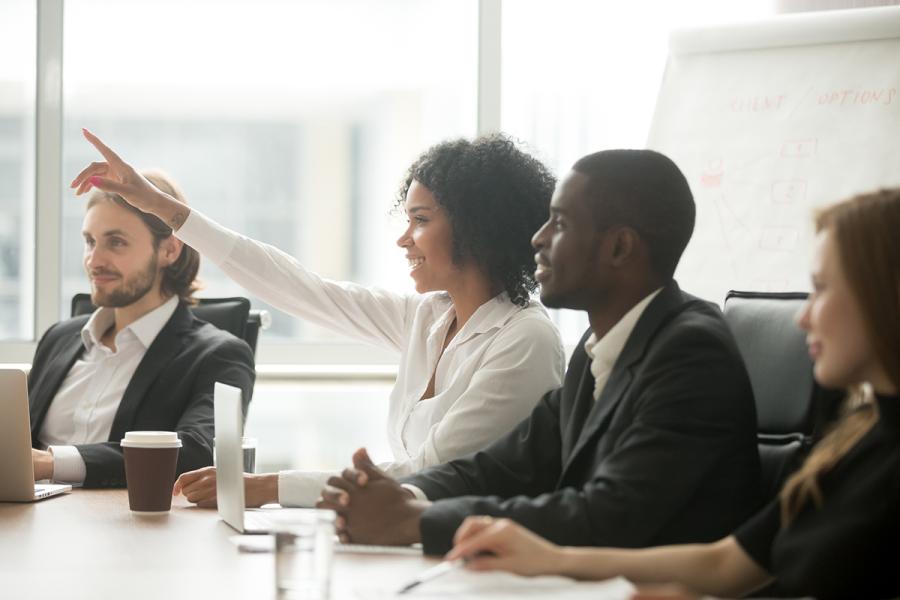 Woman in an office meeting raising her hand