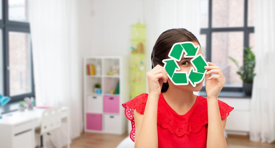 A girl looks through a cutout of a recycling symbol
