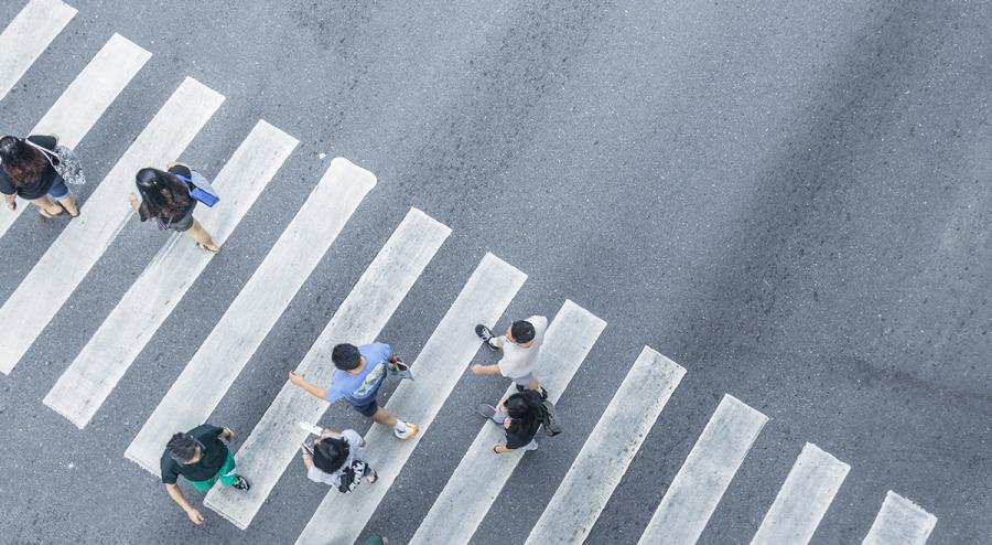 An aerial view of pedestrians walking in a crosswalk
