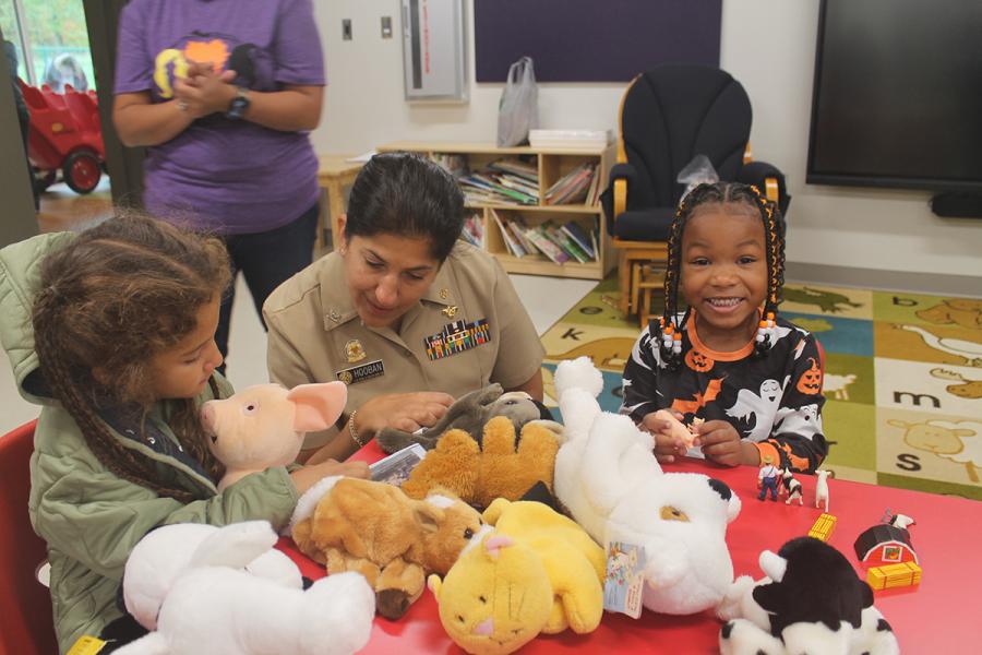 Young children and an adult at a table with stuffed animals