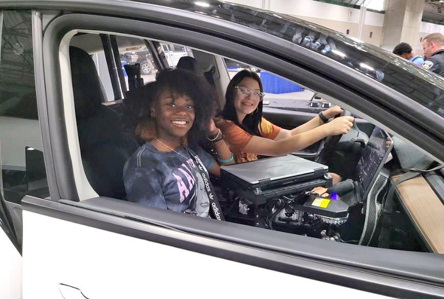 Two teens smile as they sit in a car at the 2023 Career Expo
