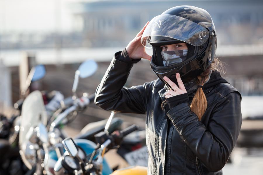 A woman putting a motorcycle helmet on