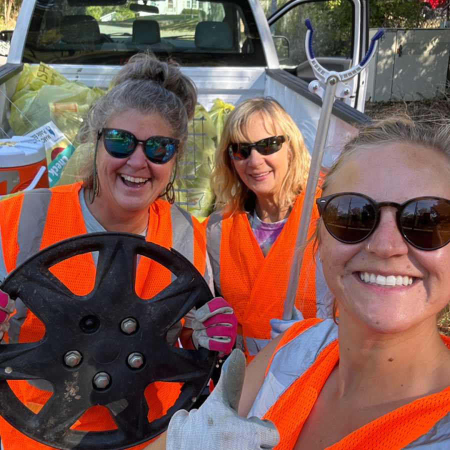 Volunteers in orange vests pose with found garbage items in Platte County