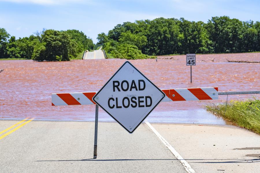 Road closed sign with flooded area in the background